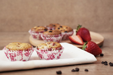 Obraz na płótnie Canvas Strawberries and chocolate chip muffins on wooden background
