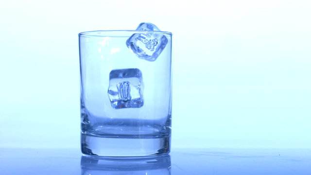 Ice cubes drop into glass, slow motion