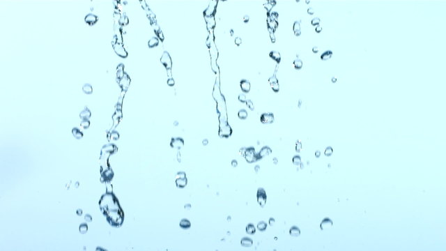 Water dripping over blue background, slow motion
