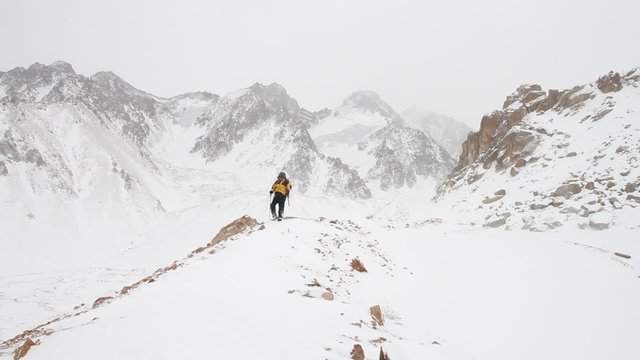 Mountaineer walking on snow-covered mountain trail during a snow storm