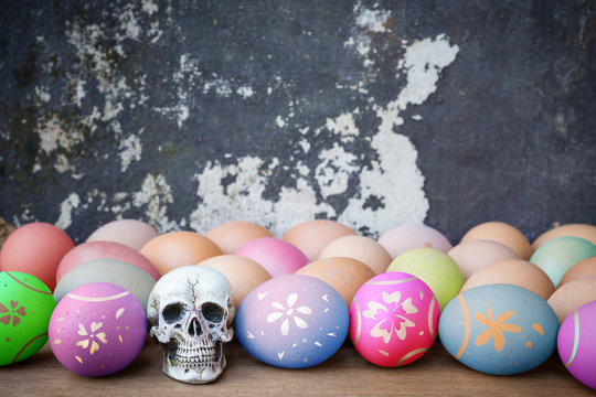 Human skull with colorful Easter eggs, Hen eggs on a wooden tabl