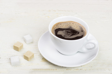 A cup of coffee on a wooden table.

A cup of coffee on an old painted,wooden,white background.