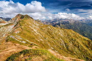 The hill covered with yellow grass with a steep slope in the Caucasus mountains