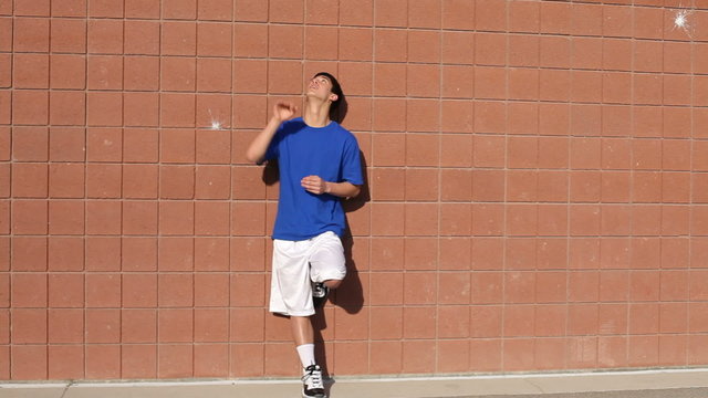 Teen standing by brick wall with basketball