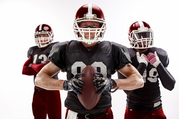 The three american football players posing with ball on white background