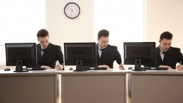 Three identical businessmen working at desks