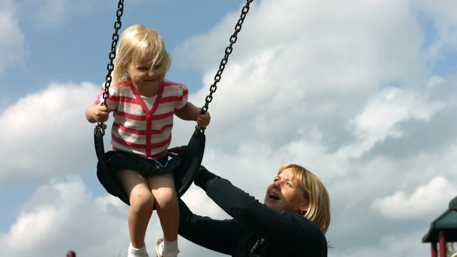 Mom pushing child on swing, slow motion