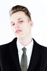 Close up picture of an elegant young fashion man wearing black suit on gray background