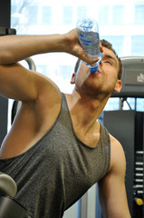 Mężczyzna na siłowni pijący wodę. - obrazy, fototapety, plakaty