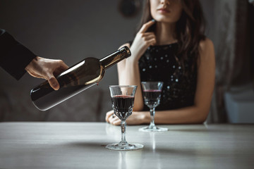 Beautiful young couple with glasses of red wine in luxury restaurant