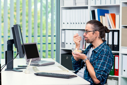 man is working in his office and eating granola