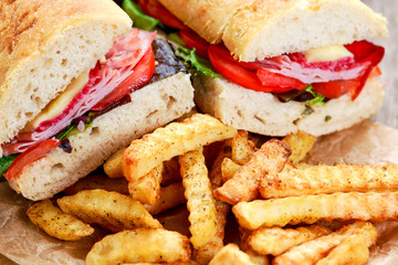 Sandwich with lettuce, slices fresh tomatoes, salami, hum and cheese