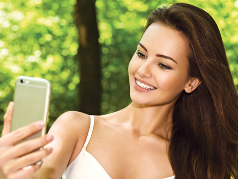 beautiful young woman selfie in the park with a smartphone
