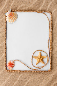 Beautiful frame of rope and star and sea shells with a white background on the sand