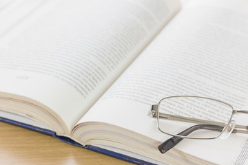 Close up glasses and open book on the desk