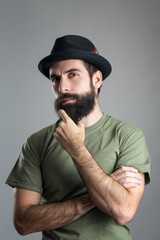 Suspicious skeptical man touching his beard looking at camera.  Headshot portrait over gray studio background with vignette.