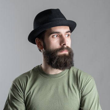 Serious pensive bearded man looking away.  Headshot close up portrait over gray studio background.