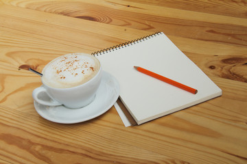 Air cappuccino for productive work/cappuccino and a notebook with a pencil on a wooden table