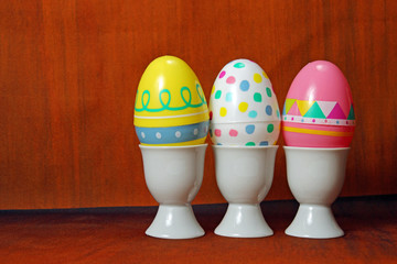 Three Easter eggs on a brown background with copy space
