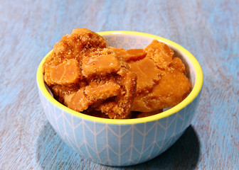 Sweet Jaggery in a bowl on a blue wooden board