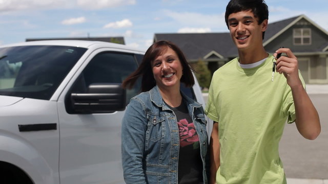Mother and son, teen holds up keys to truck