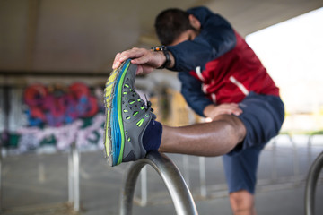 Young man stretching his legs after workout and jogging.