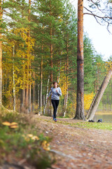 Young woman run in autumn the forest in sunset lights