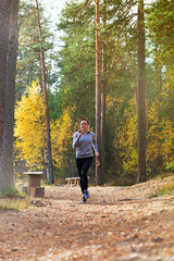 Young woman run in autumn the forest in sunset lights