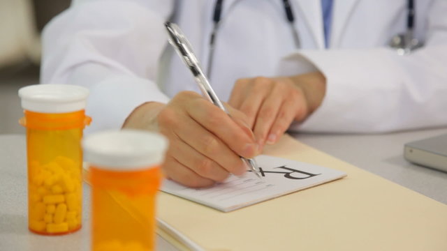 Doctor writing a prescription at desk, close up