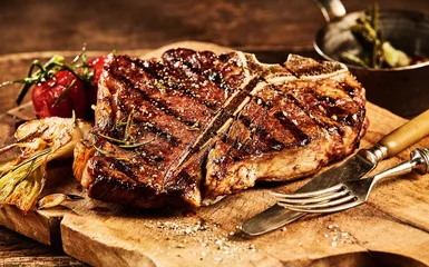 Rolgordijnen Sappige gegrilde t-bone steak met vork en mes © exclusive-design
