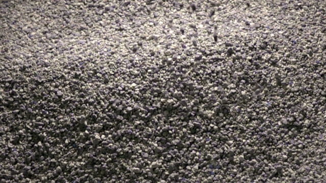The granular cement crumb pours (filling of a cat's toilet tray), slow motion 