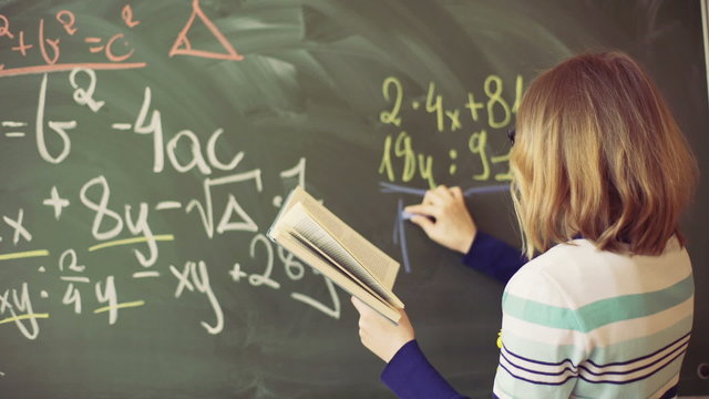 Teacher writing numbers and explaining it to the students
