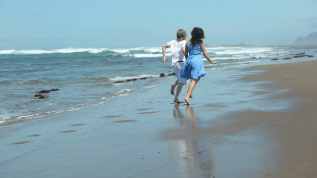 Couple holding hands and running on beach together