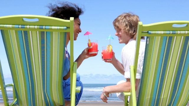 Couple sitting in beach chairs with tropical drinks