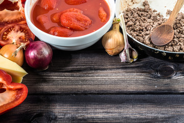 Ingredients of spaghetti bolognese arranged on wooden table.