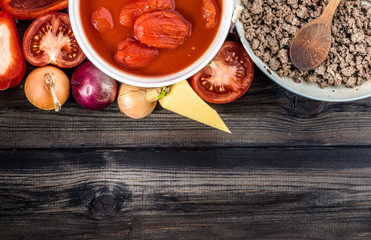 Ingredients of spaghetti bolognese arranged on wooden table.