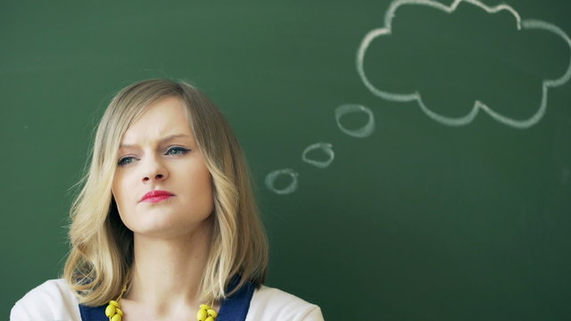 Teacher standing next to the blackboard and thinking
