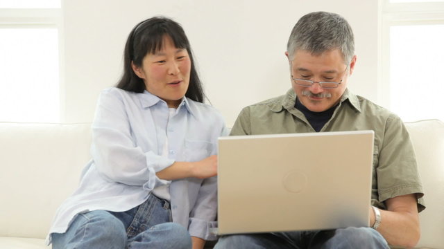 Mature Asian couple using laptop computer