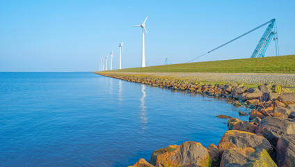Wind turbines under construction along a lake