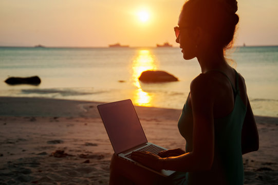 Lady With A Laptop On The Beach On The Sunset