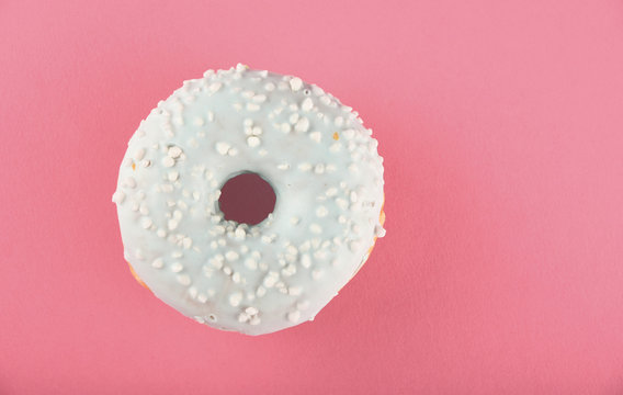 Donut with blue glaze sprinkles on pink paper