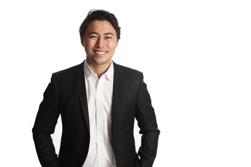 A young and professional businessman standing in front of a white background smiling looking at camera.
