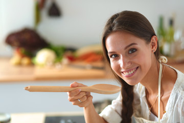 Cooking woman in kitchen with wooden spoon