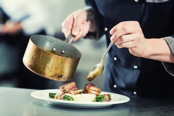 Poster Chef pouring sauce on dish in restaurant kitchen © Kzenon