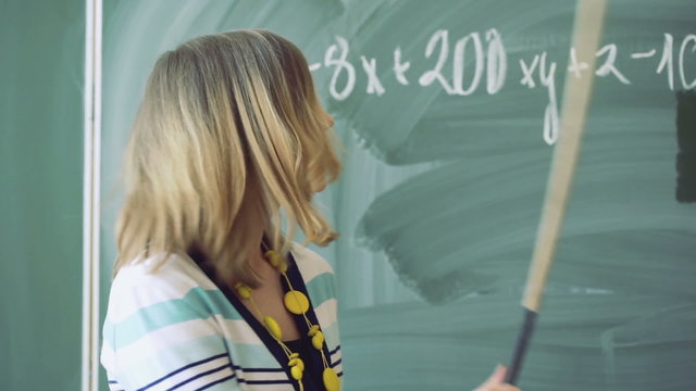 Math teacher standing next to the board and having a lecture, steadycam shot
