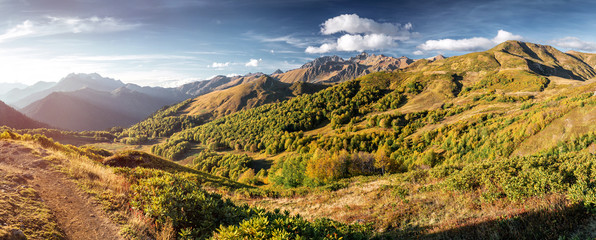 The picturesque steppe mountains landscape with multicolored mountains, sparse vegetation on the background of other mountains and cloudy sky in autumn