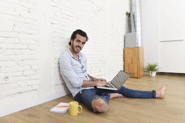 young man in hipster modern casual style look sitting on living room home floor working on laptop