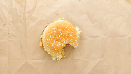 bitten off  burger on paper background. Top view