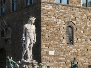 Naklejka premium Marble Statue of Neptune in Florence: A brighly lit statue of the god Neptune in the famous Piazza della Signoria in Florence