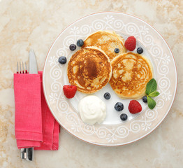 pancakes with sour cream on the plate with raspberries and blueb